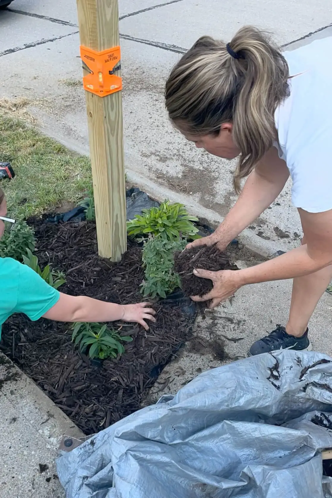 Adding mulch to a landscaped bed around a mailbox.